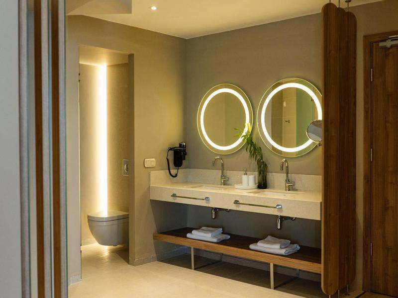 Moderner Außenbereich mit Bar, Stühlen und grüner Bepflanzung an einem sonnigen Tag.