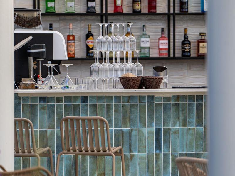 Moderner Hotelbarbereich mit türkisfliesen und leeren Stühlen vor der Bar