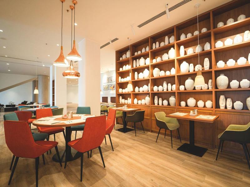 Moderner Essbereich mit bunten Stühlen und Regal voller Vasen an der Wand.