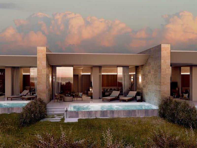 Moderner Hotelkomplex mit privaten Pools und Sitzbereichen vor einem bewölkten Himmel bei Sonnenuntergang.