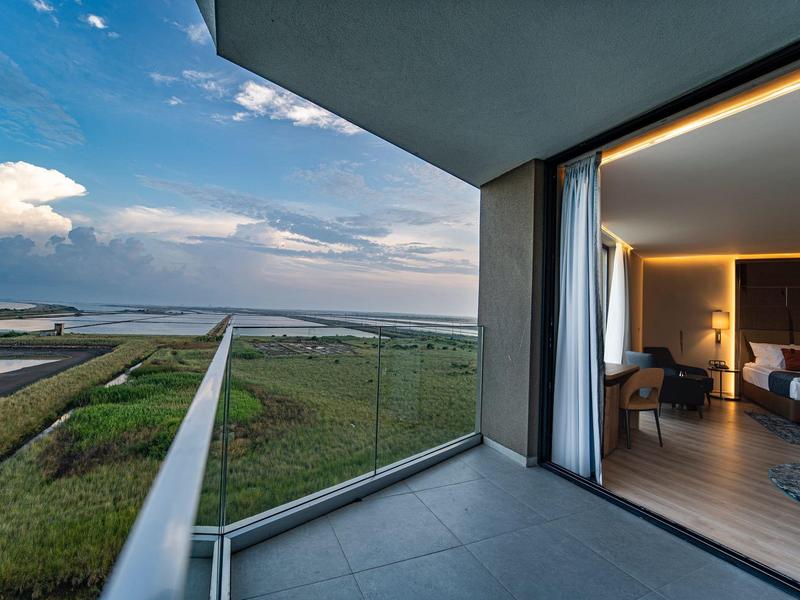 Balkon mit Glasgeländer bietet Meerblick und Zugang zu modernem Schlafzimmer.