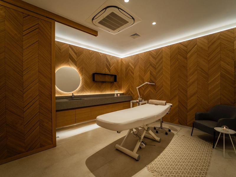 Moderne Behandlungsraum mit Massagebank, Holzvertäfelung und warmem Licht.