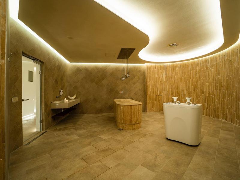 Moderner Wellnessraum mit Holzbadewanne und stimmungsvoller indirekter Beleuchtung.