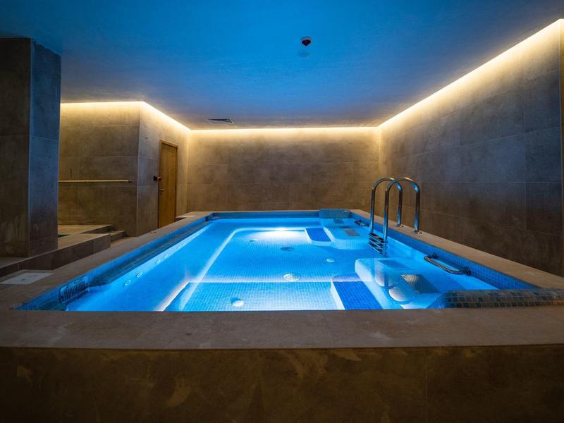 Moderner Wellness-Pool mit blauer LED-Beleuchtung in einem luxuriösen Spa-Raum.