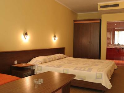 Bedroom with double bed, nightstand, wardrobe, and orange chair in a hotel room.