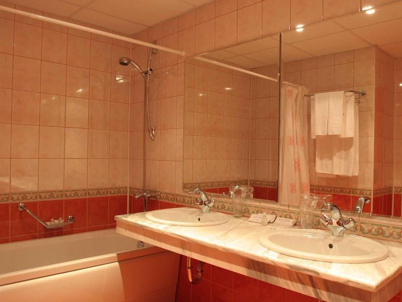 Modern bathroom with double sink, large mirror, and bathtub with shower curtain.