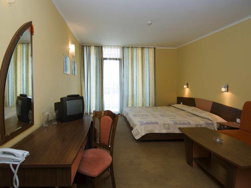 A simply furnished hotel room with double bed, desk, chairs, and television.