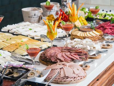 Buffet con vari affettati, piatti di formaggi e spiedini di frutta decorativi in un hotel.