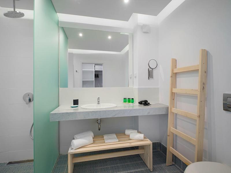 Helles Badezimmer mit großem Spiegel, Holzleiter, Waschbecken und grüner Glaswand.