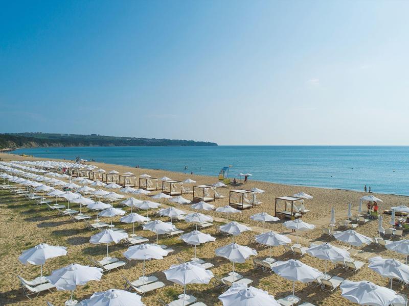 Strand mit Reihen von Liegestühlen und Sonnenschirmen am Meer an einem sonnigen Tag.