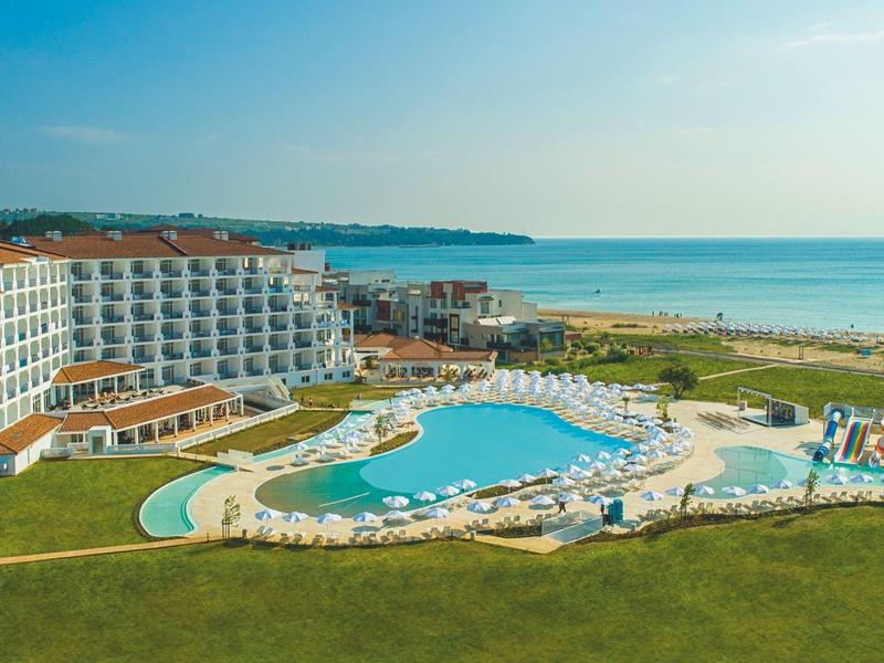 Großes Hotel mit mehreren Stockwerken neben einem Pool und Strand mit Meerblick.