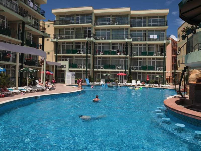 Large outdoor pool in front of a modern hotel building under a blue sky.