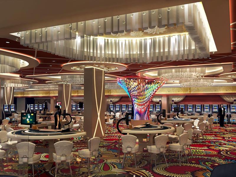 Moderner Casino- Innenraum mit Spielautomaten, runden Tischen und farbenfrohem Teppichmuster.