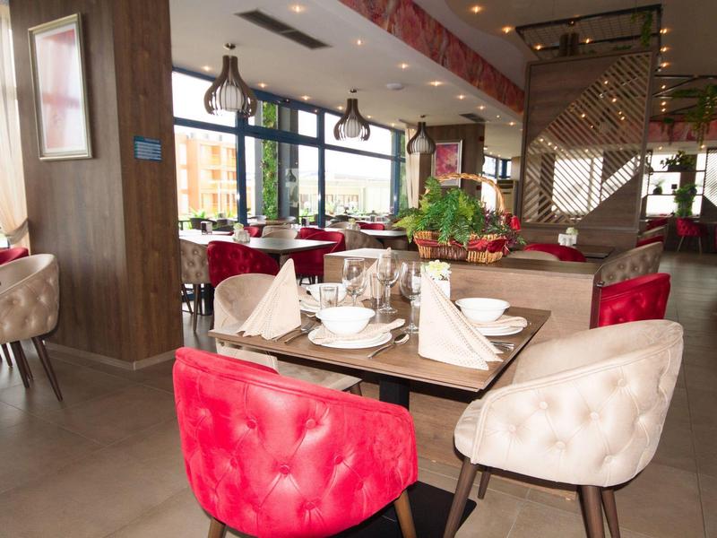 Modernes Restaurant mit roten und weißen gepolsterten Stühlen und gedeckten Holztischen.