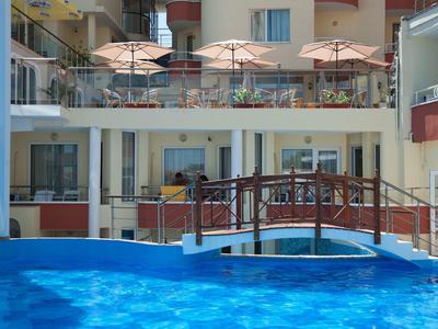 Una piscina con un piccolo ponte e ombrelloni davanti a un edificio dell'hotel.
