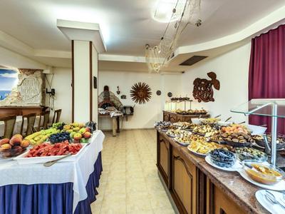 Area buffet con una varietà di piatti e frutta fresca in un ristorante dell'hotel.