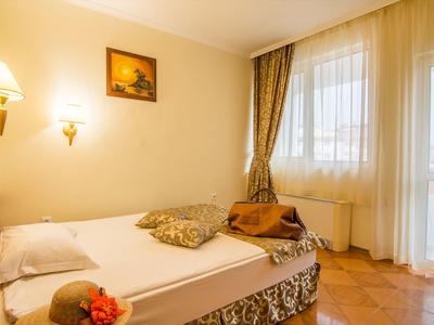 Camera d'hotel luminosa con letto singolo, comodino e tende alla finestra e alla porta del balcone