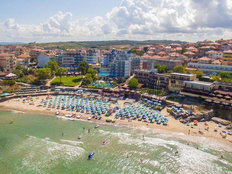 Spiaggia con lettini e hotel lungo la costa in una giornata di sole.