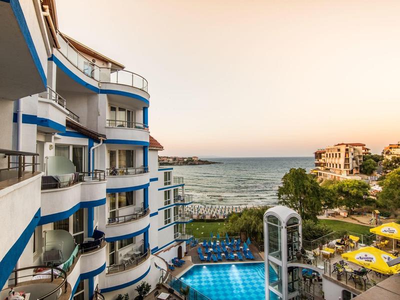 Vista di un hotel con piscina e mare al tramonto.