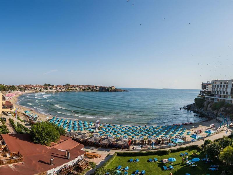 Vista panoramica di una spiaggia con lettini e ombrelloni lungo la costa sotto un cielo limpido.