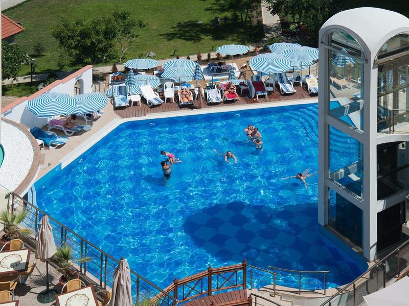Piscina blu vivace dell'hotel con scivolo d'acqua e lettini all'aperto