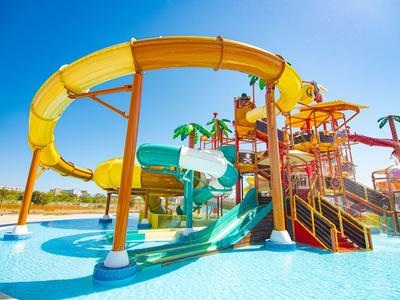 Scivoli d'acqua colorati e struttura gioco in una piscina con tempo soleggiato.