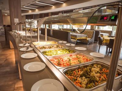 Buffet met diverse gerechten en borden in een moderne eetruimte.
