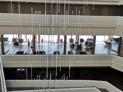 Moderne hotel lobby met zitgedeelte op meerdere niveaus, grote ramen en hangende lampen.