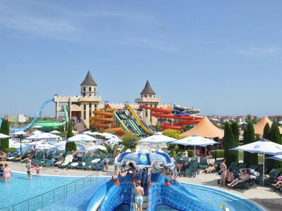 Waterpark met glijbanen, parasols en mensen die van de zonnige dag genieten.
