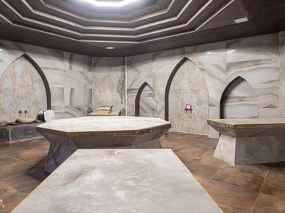 Luxe spa kamer met stenen massagetafels en gewelfde marmeren muren.