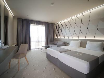 Moderne hotelkamer met twee bedden, een stoel, bureau en balkon met natuurlijk licht