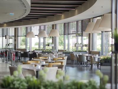 Ampia sala da pranzo moderna con tavoli, sedie e grandi finestre