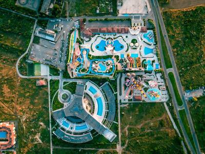 Luchtfoto van een groot waterpark met zwembaden, glijbanen en omliggende groene gebieden.
