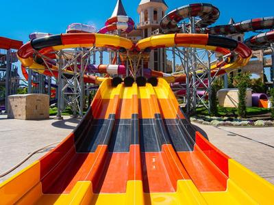 Kleurrijke meerbaans glijbaan in een waterpark onder een heldere blauwe lucht.