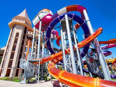 Kleurrijke waterglijbanen en een toren onder een klare blauwe lucht in een waterpark.