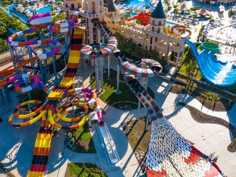 Een kleurrijk pretpark met glijbanen en een kasteelsstructuur.