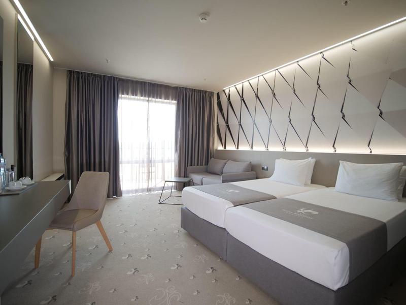 Moderne hotelkamer met twee bedden, een stoel, bureau en balkon met natuurlijk licht