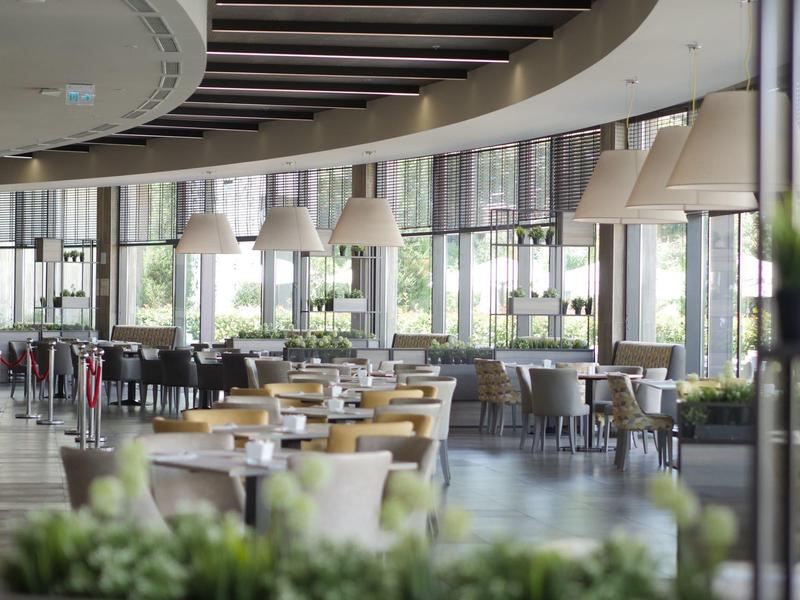 Ruim hotelrestaurant met moderne meubels en grote ramen die natuurlijk licht binnenlaten.