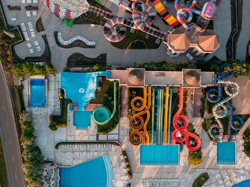 Luchtfoto van een groot waterpark met meerdere zwembaden, glijbanen en kronkelende waterbanen.