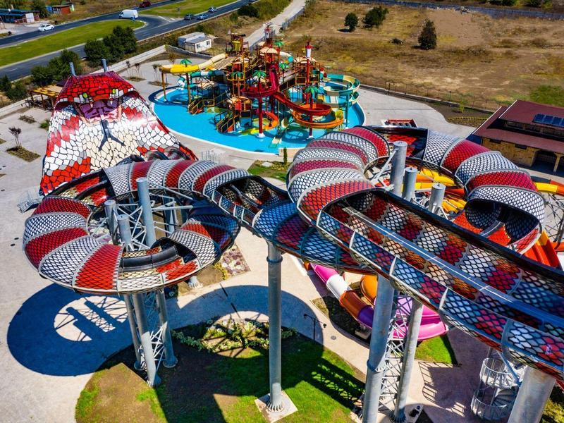 Luchtfoto van een kleurrijk waterpark met grote kronkelende glijbanen en een splashzone.