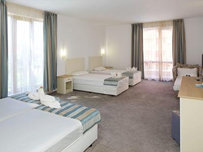 Helles Hotelzimmer mit zwei Einzelbetten, großem Fenster und Balkon.