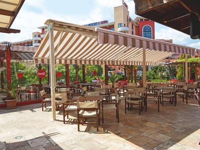 Überdachter Außenbereich eines Cafés mit vielen Tischen und Stühlen auf einem gepflasterten Bereich.