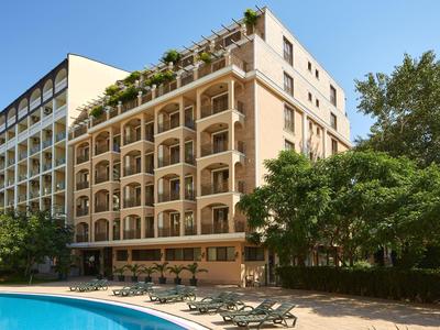 Hotel mit Balkonzimmern und einem Poolbereich mit Liegestühlen im Freien.