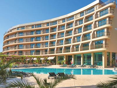 Modernes Hotel mit geschwungener Fassade und großem Außenpool bei klarem Himmel.