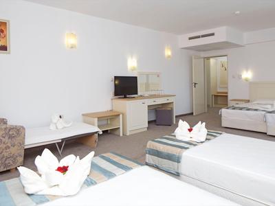 Helles Hotelzimmer mit zwei Betten, einem Fernseher und moderner Einrichtung.