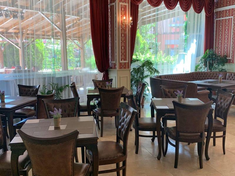 Heller Essbereich mit dunkelroten Vorhängen und Holzstühlen in einem Hotelrestaurant.