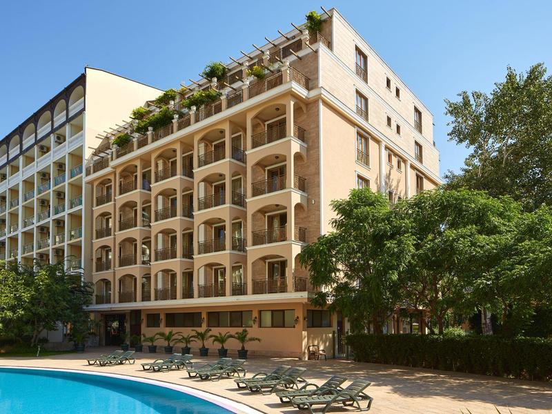 Hotel mit Balkonzimmern und einem Poolbereich mit Liegestühlen im Freien.