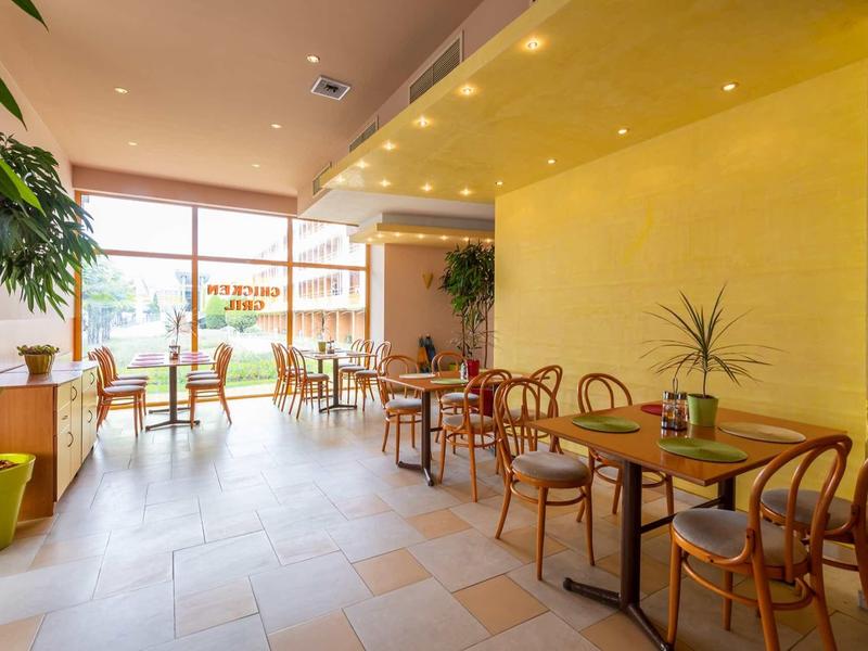 Brightly lit dining area with wooden tables and chairs in a modern café or restaurant.