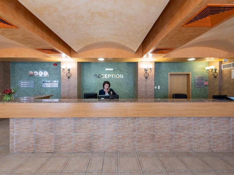 Modern hotel reception with long front desk and a staff member behind it.
