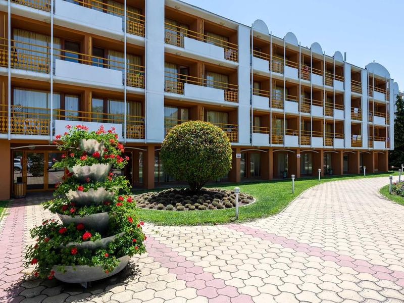 Modern hotel complex with well-maintained garden and multi-story building with balconies.